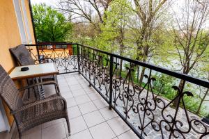 einen Balkon mit 2 Stühlen, einem Tisch und einem Fenster in der Unterkunft Apartments Villa Kobilj in Banja Luka