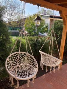 twee rieten stoelen hangend aan een veranda met een licht bij Къща за гости ЗЕЛЕНА in Vinogradets