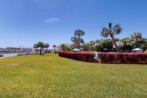 a park with red bushes and palm trees and water at Pirates Bay A104 in Fort Walton Beach