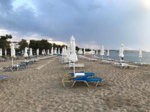 een strand met ligstoelen en parasols en de oceaan bij Tami in Neoi Epivatai