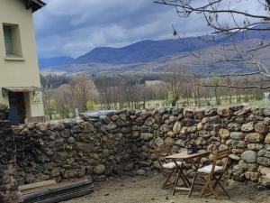 a stone wall with a table and chairs in front of it at Appartement avec chambre ouverte in Bourg-Madame