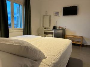 a bedroom with a bed and a desk with a mirror at Kamelia Hotel in Spetses