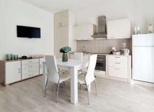 a white kitchen with a white table and chairs at Goccia Smeraldo - Gocce sul Mare in Savelletri di Fasano