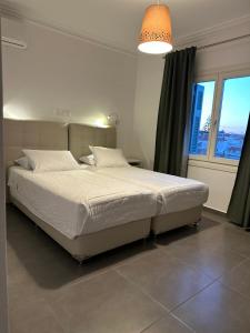 a bedroom with a large white bed with a window at Kamelia Hotel in Spetses