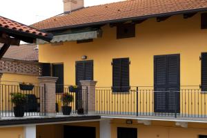 una casa amarilla con persianas negras y macetas en La casa di Marigio', 