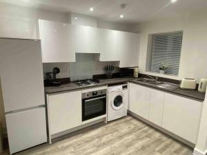 a kitchen with white cabinets and a washing machine at 3 Bed house, Derby City Centre leisure or Business in Derby