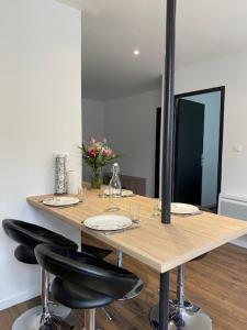 a wooden table with two chairs and a mirror at Appartement au cœur du village in Marlhes