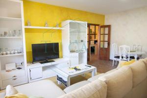 ein Wohnzimmer mit einem weißen Sofa und einem TV in der Unterkunft Villa Zahara de 3 habitaciones con Piscina in Cádiz