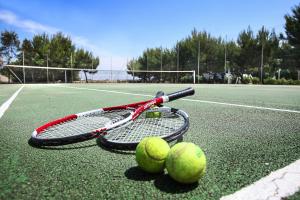a tennis racket and two tennis balls on a tennis court at Calanca Apulian Residence in Torre Santa Sabina