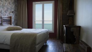 a bedroom with a bed and a large window at Hôtel Vauban in Le Palais
