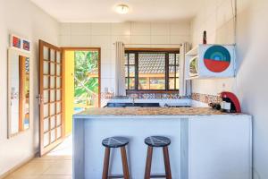 a kitchen with a blue island with two bar stools at Studios na Vermelhinha in Ubatuba