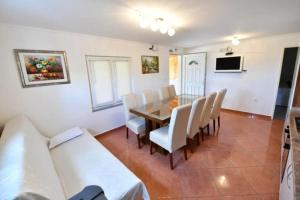 a dining room with a table and white chairs at Kovacic Villa with pool, tennis cart and free parking in Hrvace