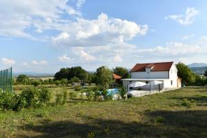 a white house with a red roof in a field at Kovacic Villa with pool, tennis cart and free parking in Hrvace