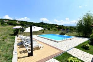 a swimming pool with chairs and an umbrella at Kovacic Villa with pool, tennis cart and free parking in Hrvace