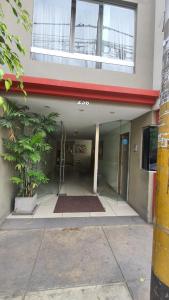 un pasillo de un edificio con una puerta y una planta en DEPARTAMENTO BREÑA POR Hospital LOAYZA, en Lima