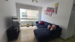 a living room with a blue couch and a window at DEPARTAMENTO BREÑA POR Hospital LOAYZA in Lima