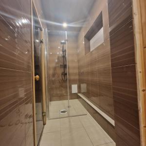 La salle de bains est pourvue d'une douche avec une porte en verre. dans l'établissement Домик с сауной для отдыха, à Katase