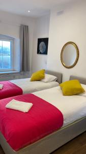 two beds with red and yellow pillows in a room at Large heritage-House close Snowdonia & Llandudno in Denbigh