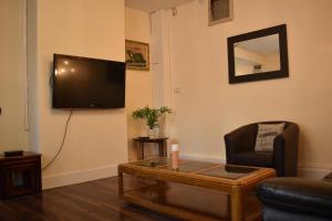 a living room with a tv and a chair and a table at Large heritage-House close Snowdonia & Llandudno in Denbigh