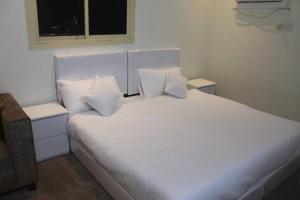 um quarto com uma cama com lençóis brancos e almofadas em شقة خاصة للعائلات فقط em Medina