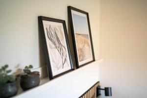 two framed pictures sitting on a fireplace mantle at Bjerrebo idyl - Romalt Bakker in Randers