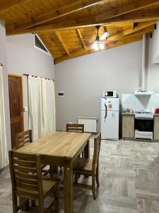 a kitchen with a wooden table and a refrigerator at Cabañas del Arroyo Villa Ventana in Villa Ventana
