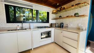 a kitchen with white cabinets and a stove top oven at Ilha do Mel Lodges in Ilha do Mel