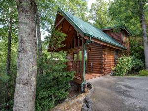 a log cabin with a porch and a green roof at Cub’s Cove, 1 Bedroom, Near Downtown, View, Jetted Tub, WiFi, Sleeps 4 in Gatlinburg