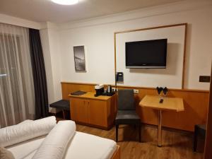 um quarto de hotel com um sofá e uma televisão em Hotel Garni Romantica em Jerzens