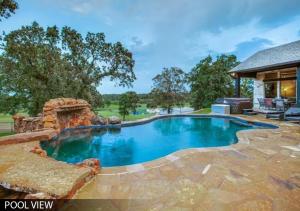a swimming pool in a backyard with a stone patio at Hilltop Ranch House - Holiday & Family Destination in Valley View