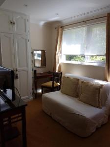 a living room with a white couch and a window at Dolphin Guest House in Looe