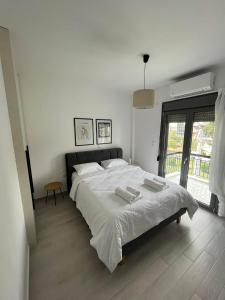 - une chambre blanche avec un grand lit et 2 serviettes dans l'établissement Tiffany's apartments -2' walk from Metro, à Athènes
