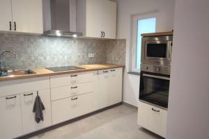 a kitchen with white cabinets and a sink and a microwave at L'escale tout confort in Charleroi