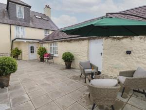 a patio with chairs and a green umbrella at Clementine Cottage in Tenby