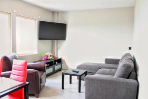 een woonkamer met 2 banken en een flatscreen-tv bij MAXIM APARTMENT in Heraklion