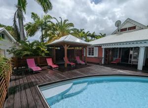 a swimming pool with chairs and a house at Villa Monet in Sainte-Rose