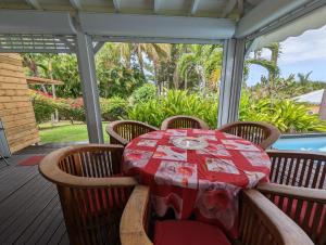 a table on a porch with a red table cloth at Villa Monet in Sainte-Rose