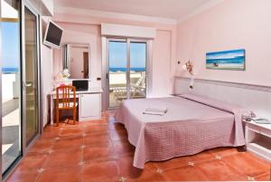 a bedroom with a bed and a desk and a balcony at Hotel Le Querce in Senigallia