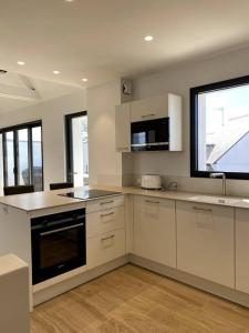 a large kitchen with white cabinets and a window at La Cabane de la Plage in Quiberon +8 photos