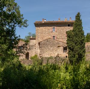 Pézenes-les-Mines的住宿－Ferme d'hôtes de Pouzes，一座古老的砖砌建筑,前面有一棵树