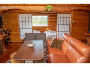 - un salon avec un canapé en cuir et une table dans l'établissement Inaka no Kakurega Cottage Hideaway - Vacation STAY 19620v, à Inakadate