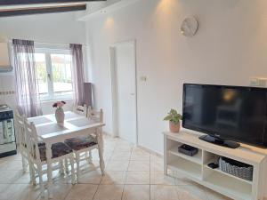 a living room with a television and a table with a dining room at Apartments Nicole in Jezera
