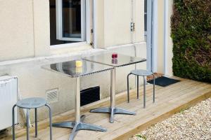 a glass table and two stools on a deck at La Maison des Plantes, charmante, atypique et cosy pour 4 personnes avec parking et jardin in Rouen
