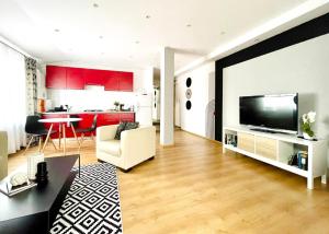 a living room with a large television and a kitchen at R&B apartment in Timişoara