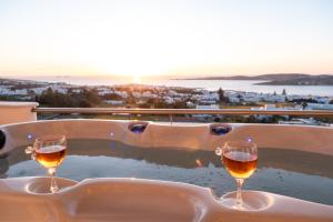 two glasses of wine sitting in a bath tub with the sunset at Panos Luxury Suite in Parikia