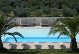 a swimming pool with lounge chairs and palm trees at Relais Le Fornacelle in Castagneto Carducci
