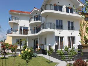a large white building with balconies and trees at Casa Servus in Mamaia Sat/Năvodari