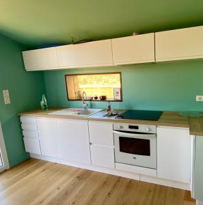 una cocina con armarios blancos y una pared verde en La Villa Moon, en Lacanau-Océan