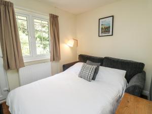 a bedroom with a white bed and a couch at Primrose Cottage in Llandrindod Wells