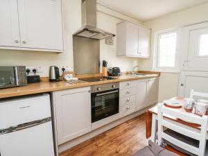 a kitchen with white cabinets and a wooden floor at Primrose Cottage in Llandrindod Wells